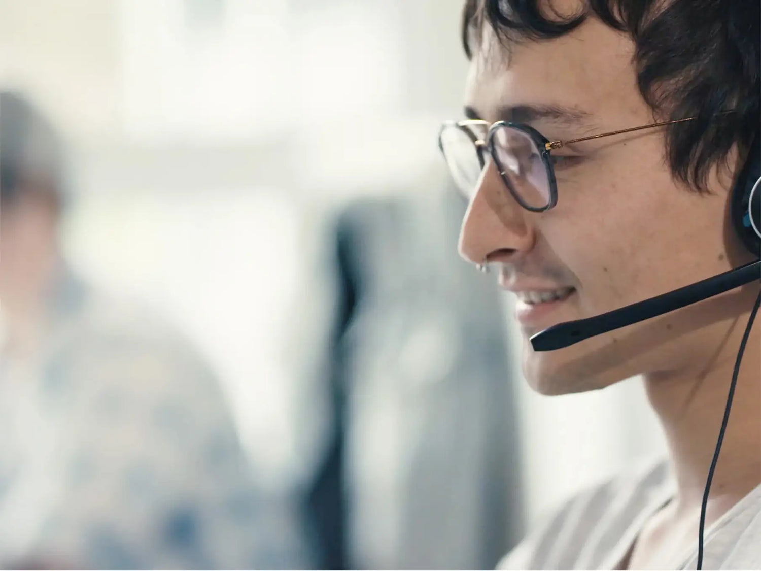 Asiakaspalvelija kuulokkeilla ja mikrofonilla työssään