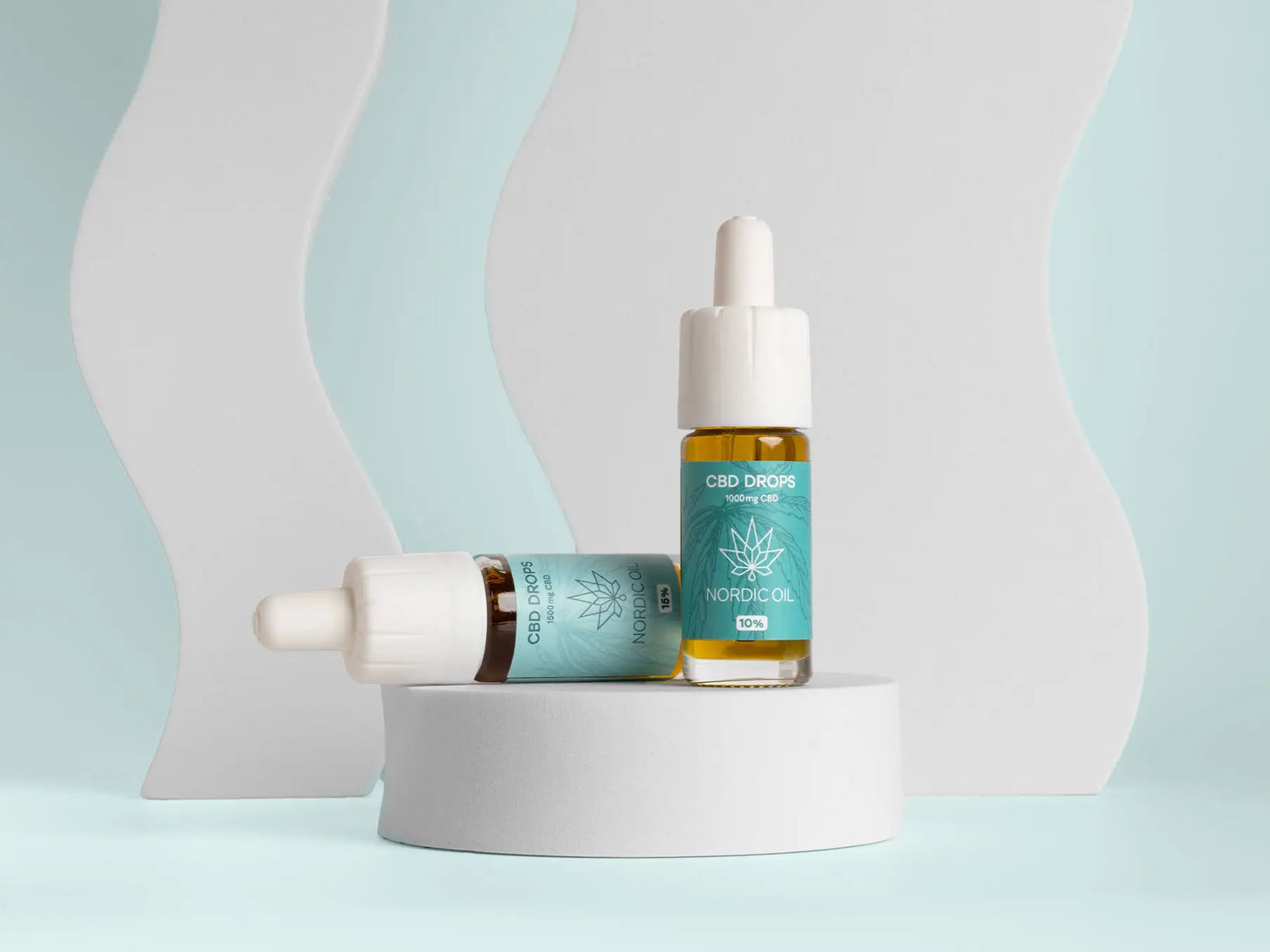 Nordic Oil CBD-droppipullot turkoosilla etiketeillä esillä valkoisella pyöreällä alustalla
