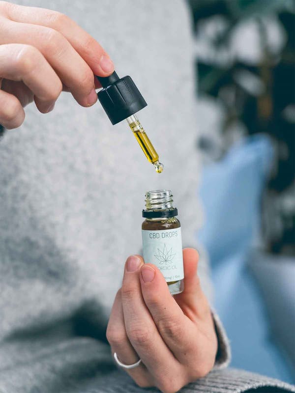 CBD-öljydroppipullo kädessä