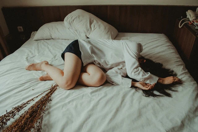 Nainen kivusta kärsien makaamassa sängyllä