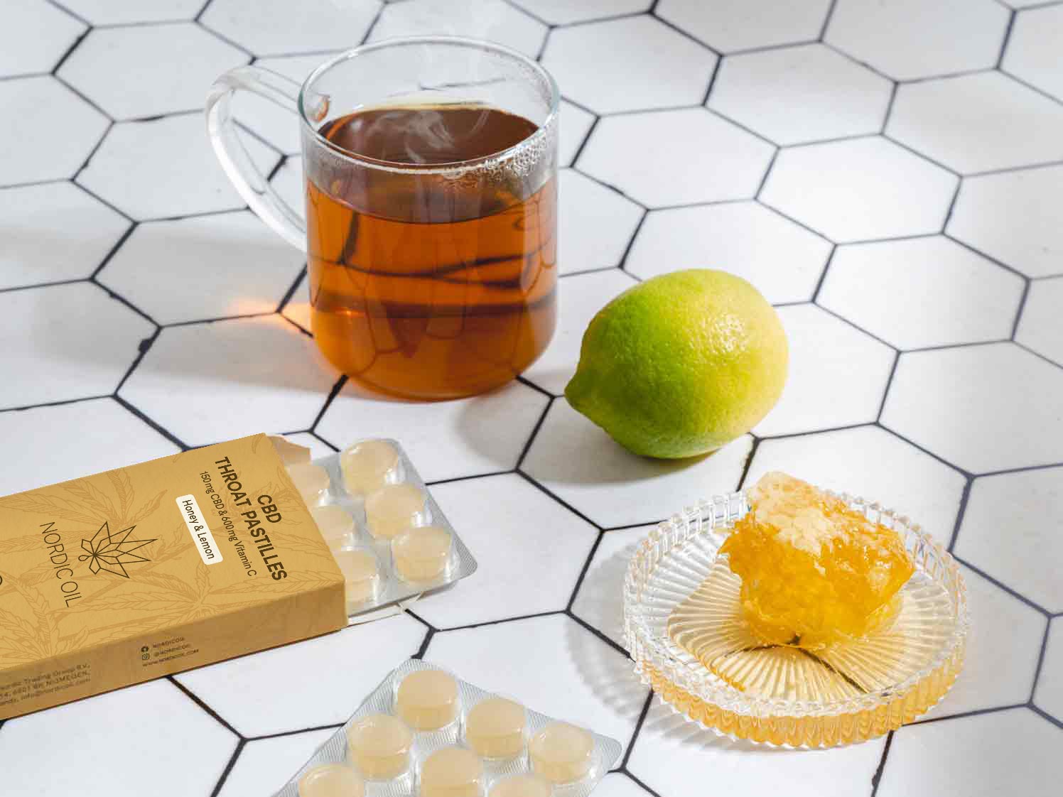 Kuppi teetä on sitruunan, hunajan ja CBD-kurkkupastillin vieressä.