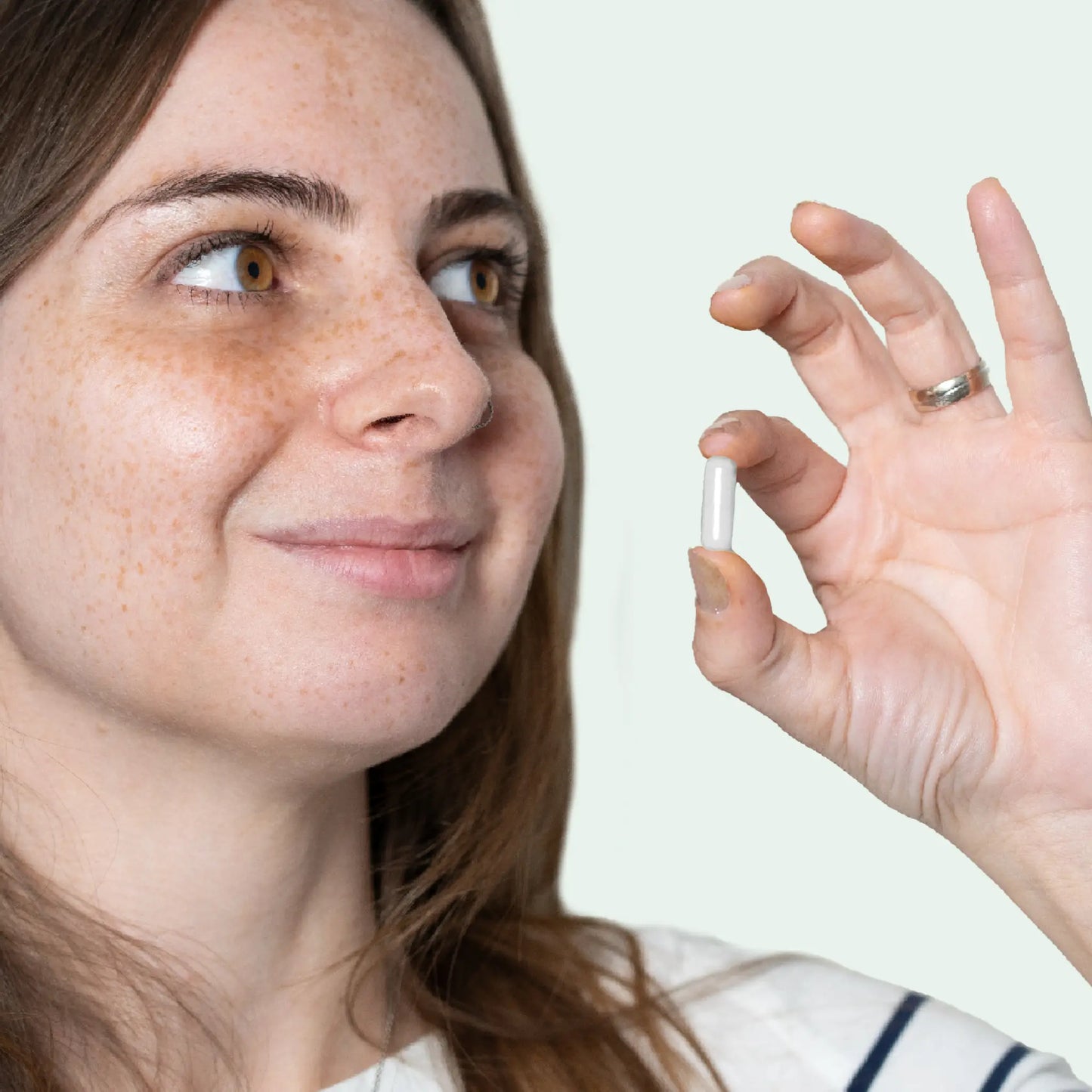 Nainen pitelee kädessään valkoista kapselia.